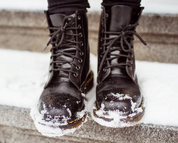 botos negras altas pisando un escalón con nieve