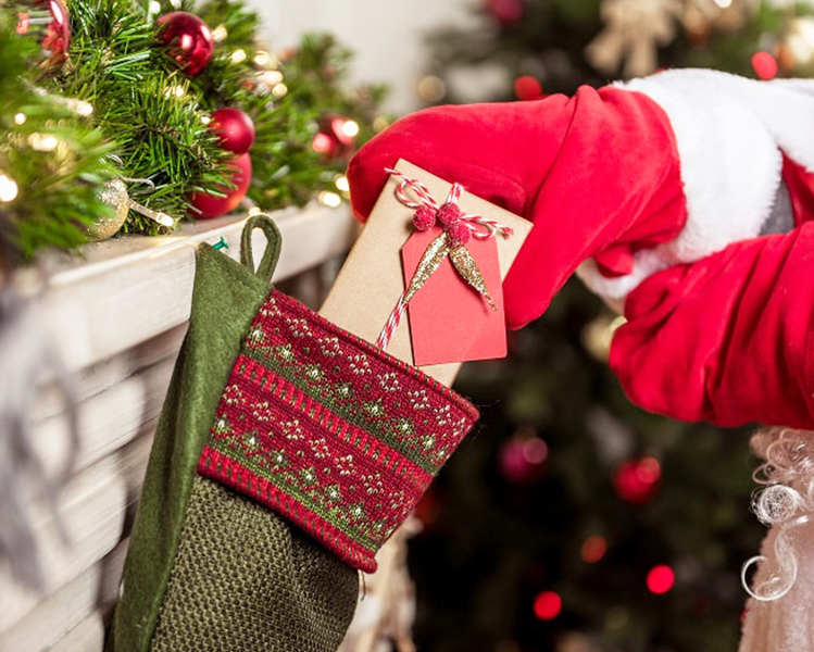 Santa Claus puts a present inside a Christmas stocking