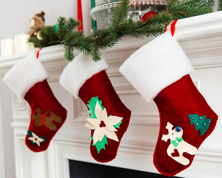 Red stockings with Christmas details hanging from a chimney of a white house