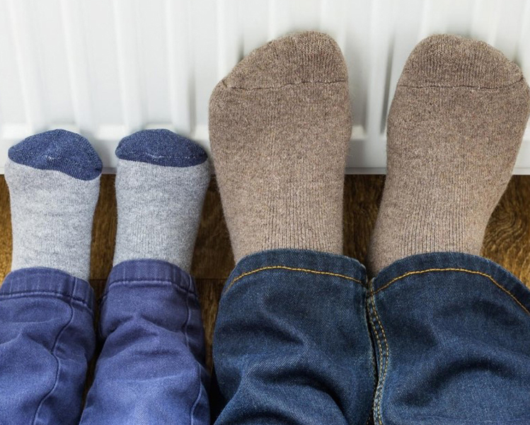 pies con calcetines de adulto y pies con calcetines de niño apoyados sobre un radiador