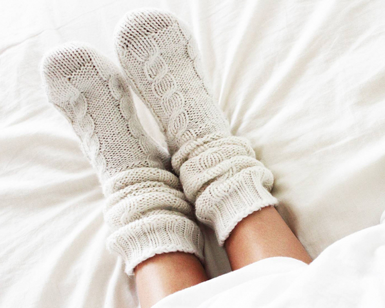Calcetines de invierno de lana sobre una cama con sábanas blancas