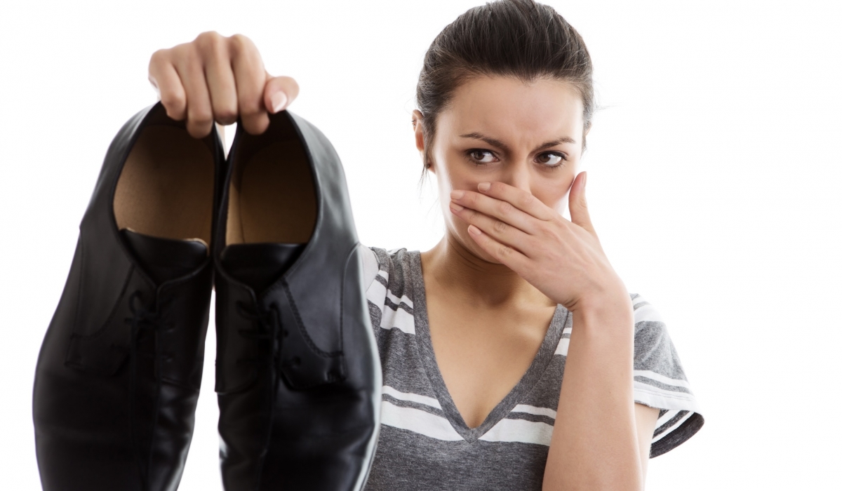 Mujer tapando la nariz y sujetando unas zapatos de hombre