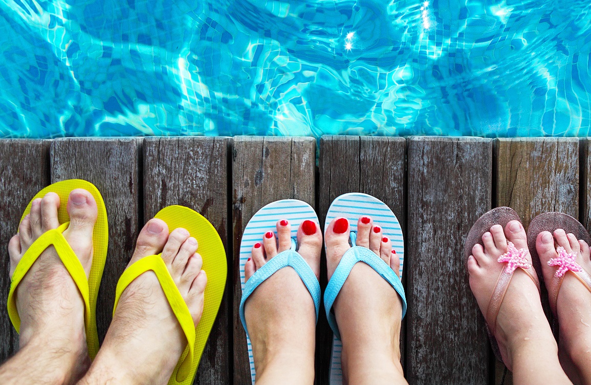 Pies con chanclas de dedo al borde de una piscina