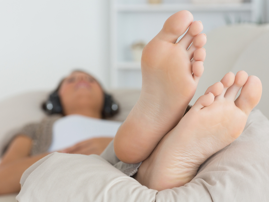 Chica escuchando música con los pies en alto